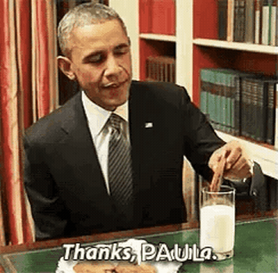 Barack Obama Is Sitting At A Desk With A Glass Of Milk And A Piece Of Food . GIF