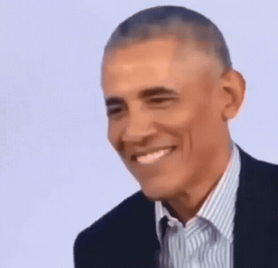 Barack Obama Is Smiling While Wearing A Suit And A Striped Shirt . GIF