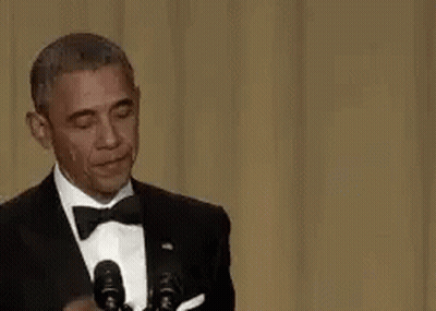 Barack Obama Is Wearing A Tuxedo And Bow Tie While Giving A Speech In Front Of Microphones . GIF