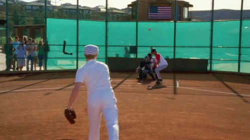 Baseball Game On Field With American Flag Behind Fence GIF