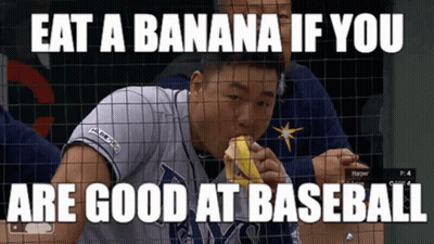 Baseball Player Eating Banana Behind Fence GIF