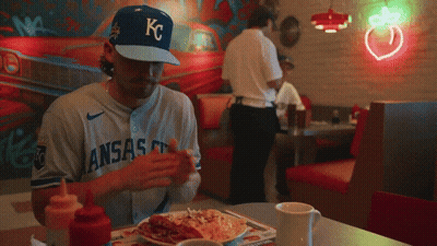 Baseball Player In KC Hat Sitting At Table GIF