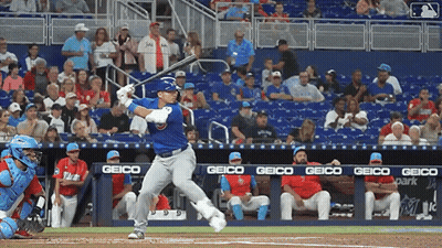 Baseball Player Swinging At Pitch With Geico Banner GIF
