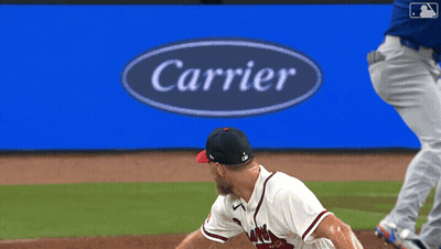 Baseball Player Throwing Pitch In Front Of Carrier Sign GIF