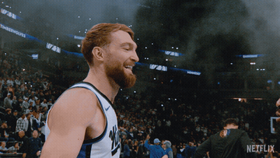 Basketball Player Smiling In Front Of Crowd With Netflix Logo GIF