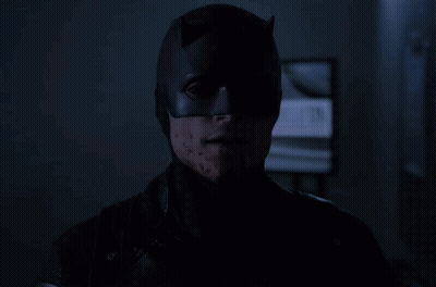 Batman Mask Man Stares At Camera In Dark GIF