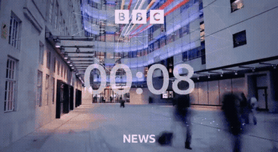 BBC News Screen With People Walking Past Building GIF