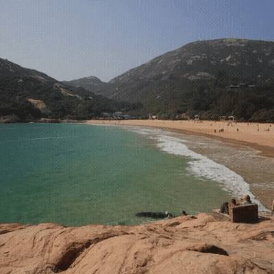 Beach With Mountains And People In Water GIF