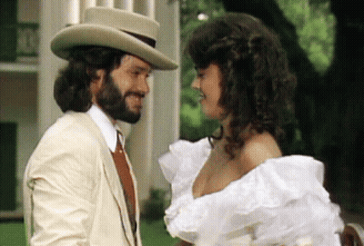 Bearded Man And Woman In White Dress Looking At Each Other GIF