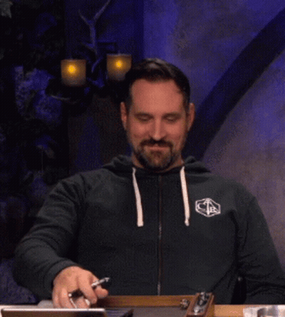 Bearded Man At Table With Phone And Pen GIF