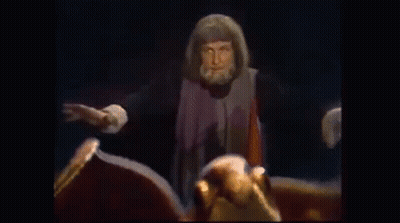 Bearded Man Beside Dragon Statue With Spread Wings GIF