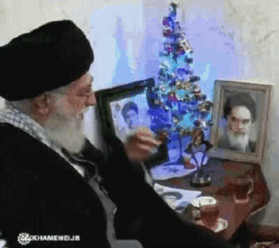 Bearded Man By Christmas Tree With Two Framed Pictures GIF