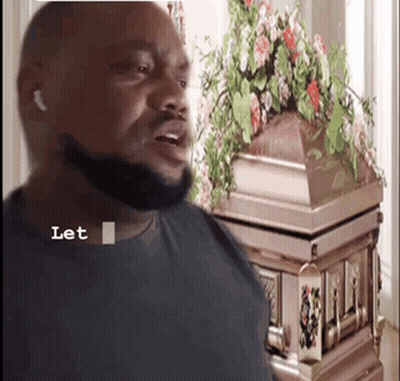 Bearded Man By Coffin With Flowers GIF