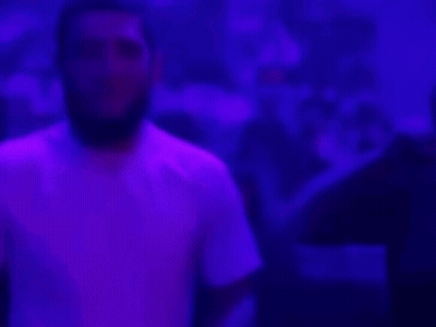 Bearded Man Covering Ears In Dark Room GIF