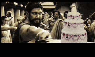 Bearded Man Cutting Cake in Front of Crowd