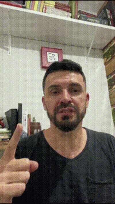 Bearded Man Giving Thumbs Up In Front Of Bookshelf GIF