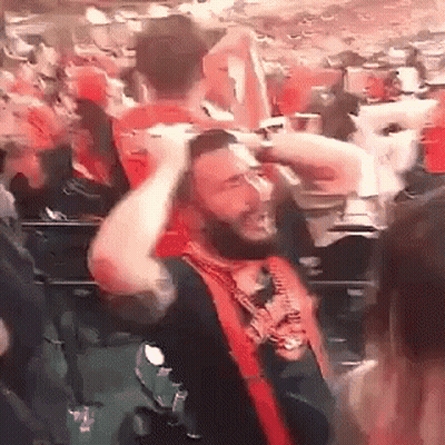 Bearded Man Holding Head In Crowd GIF