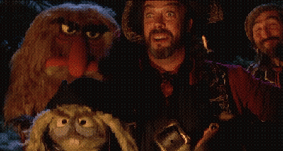 Bearded Man Holding Stuffed Animal In Front Of Muppets GIF