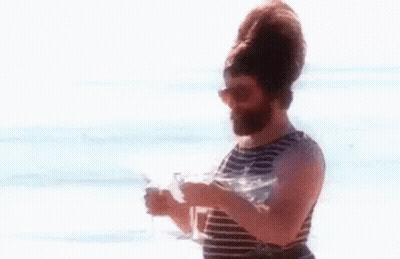 Bearded Man Holding Two Wine Glasses On Beach GIF