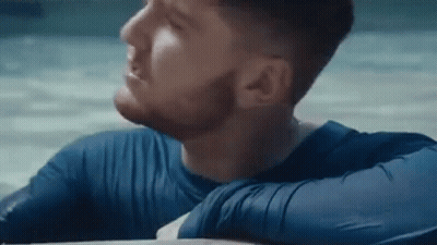 Bearded Man In Blue Shirt Sitting On Beach GIF