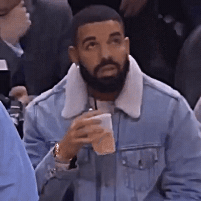 Bearded Man In Denim Jacket Holding Coffee In Crowd GIF