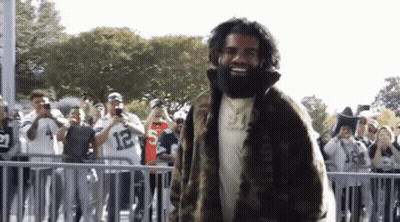 Bearded Man In Fur Coat Before Crowd GIF