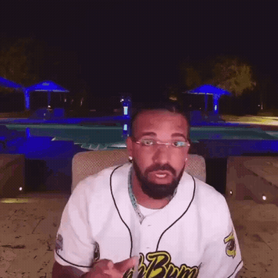 Bearded Man In Glasses Sitting By Pool At Night GIF