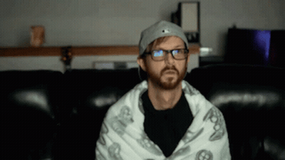 Bearded Man In Glasses Wrapped In Blanket On Couch GIF