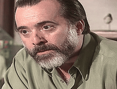 Bearded Man In Green Shirt Looking At Camera GIF