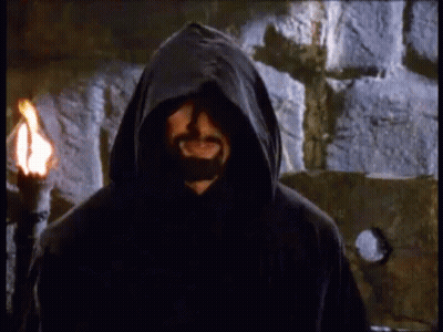 Bearded Man In Hood With Torch By Stone Wall GIF