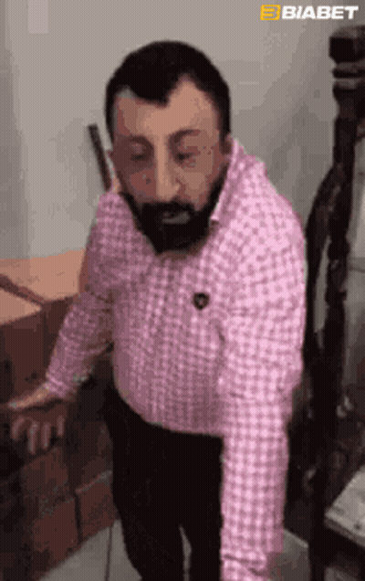 Bearded Man In Pink Shirt Standing With Boxes GIF