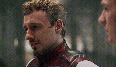 Bearded Man In Red And Black Suit Talking To Another Man GIF