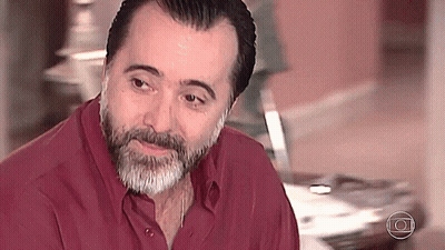 Bearded Man In Red Shirt Looking At Camera GIF