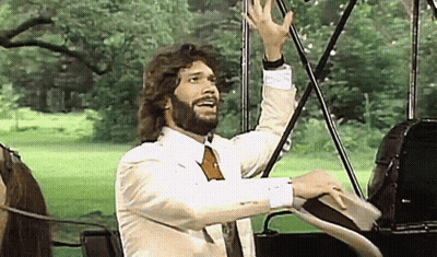 Bearded Man In Suit And Tie In Front Of Horse-Drawn Carriage GIF