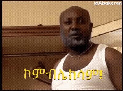 Bearded Man In White Tank Top And Necklace Beside Closet GIF