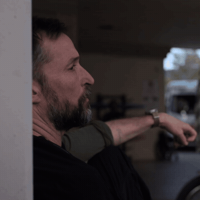 Bearded Man Leaning Against Wall Wearing Watch GIF