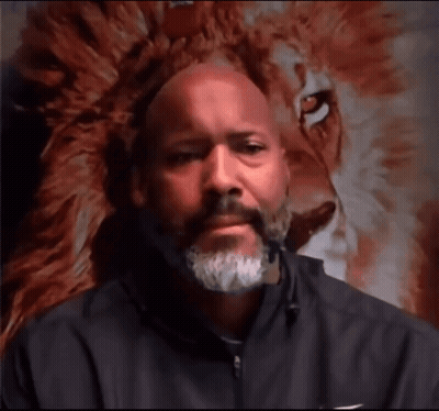 Bearded Man Looking At Camera In Front Of Lion Painting GIF