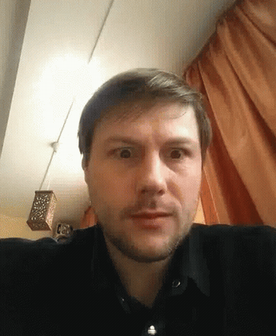 Bearded Man Making Funny Face In Front Of Orange Curtains GIF