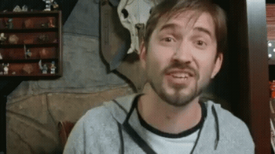 Bearded Man Making Funny Face in Front of Shelf With Figurines