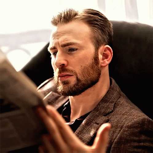 Bearded Man Reading Newspaper In Chair GIF