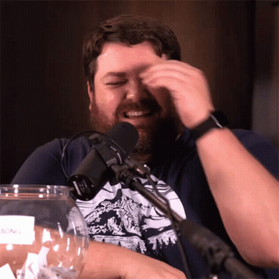 Bearded Man Sitting at Microphone With Glass