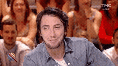 Bearded Man Sitting Before Crowd GIF