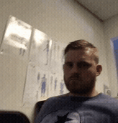 Bearded Man Sitting In Chair Before Wall Drawings GIF