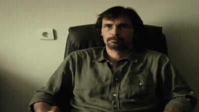 Bearded Man Sitting In Chair With Hands In Pockets GIF
