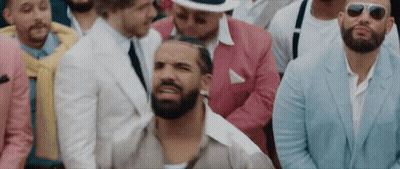 Bearded Man Sitting In Crowd Of Suited Men With Sunglasses GIF