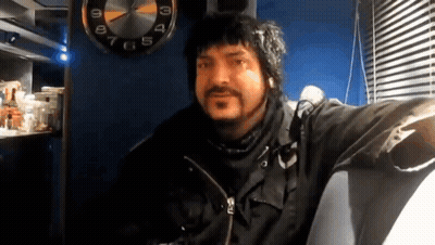 Bearded Man Sitting In Front Of Clock At 1 And 3 GIF