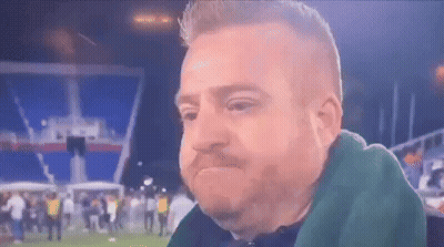Bearded Man Sitting In Front Of Crowd On Soccer Field GIF