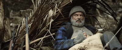 Bearded Man Sitting In Pile Of Branches GIF