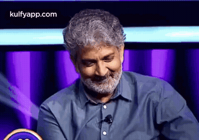 Bearded Man Smiling At Microphone On Stage GIF