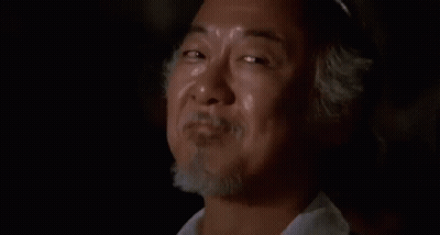 Bearded Man Smiling In Dark Room With Another Man GIF